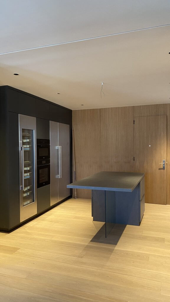 Cocina con isla central negra y electrodomésticos empotrados en Casa Freixa