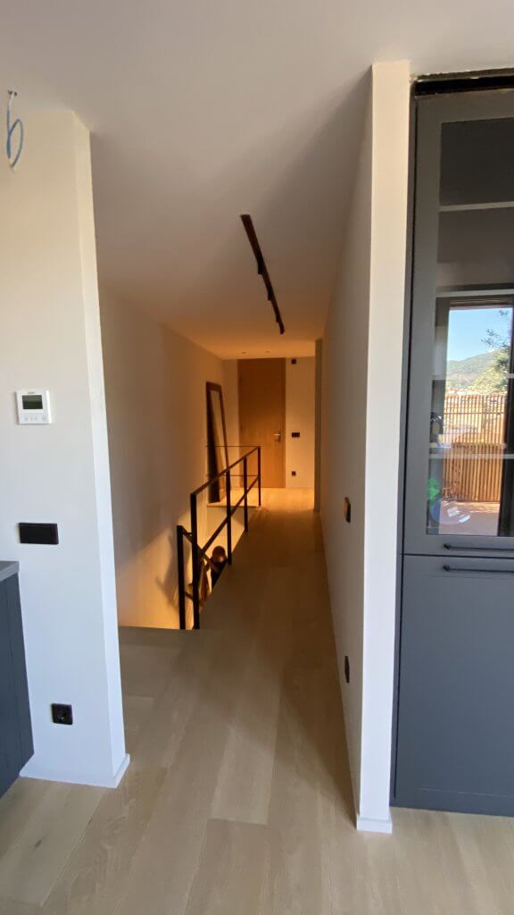 Distribuidor reformado con acceso a escaleras y luz cálida - Casa Freixa