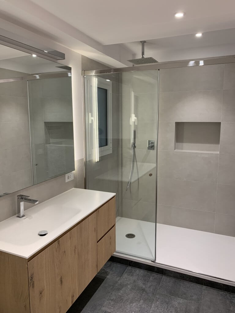 baño moderno con mueble de madera y ducha de obra con mampara de cristal