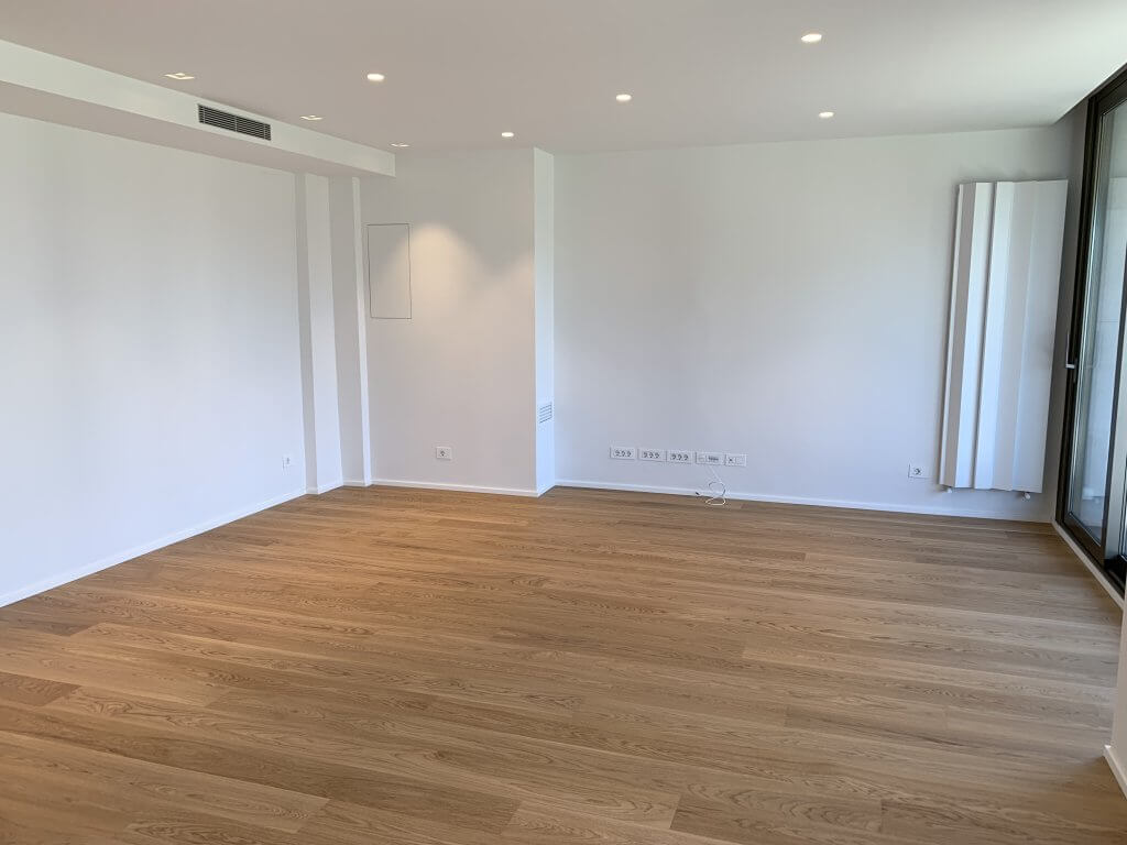 salón moderno vacío con suelo de madera clara y luz natural