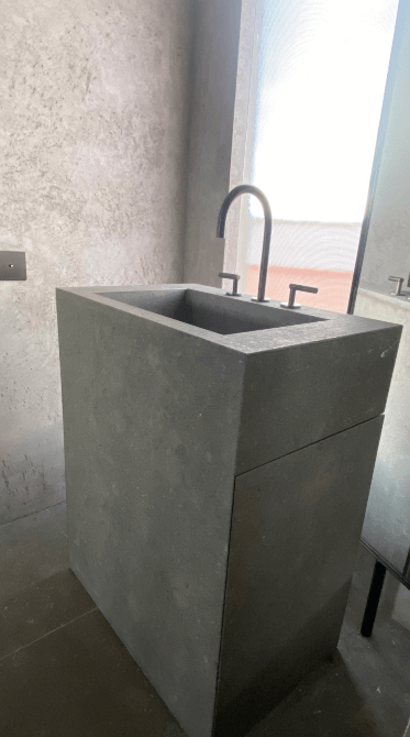 Lavabo de microcemento gris oscuro con grifería negra y ventana translúcida